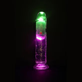 The RealRock Wireless Rechargeable LED Vibrating 7" by Shots America stands upright, glowing with green and purple LEDs against a dark background.